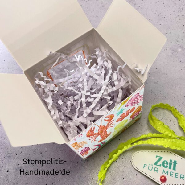 Handdekorierte Fensterschachtel 7 cm mit maritimen Motiven, Geschenkbox mit Fenster und Schleife in Grün, Detailansicht Geschenkschachtel Etikett „Zeit für Meer“, Offene Sichtfensterbox von oben, Fensterschachtel mit bunter Meeresdekoration, Geschenkverpackung mit transparentem Fenster, Handgemachte maritime Fensterschachtel mit Schleife